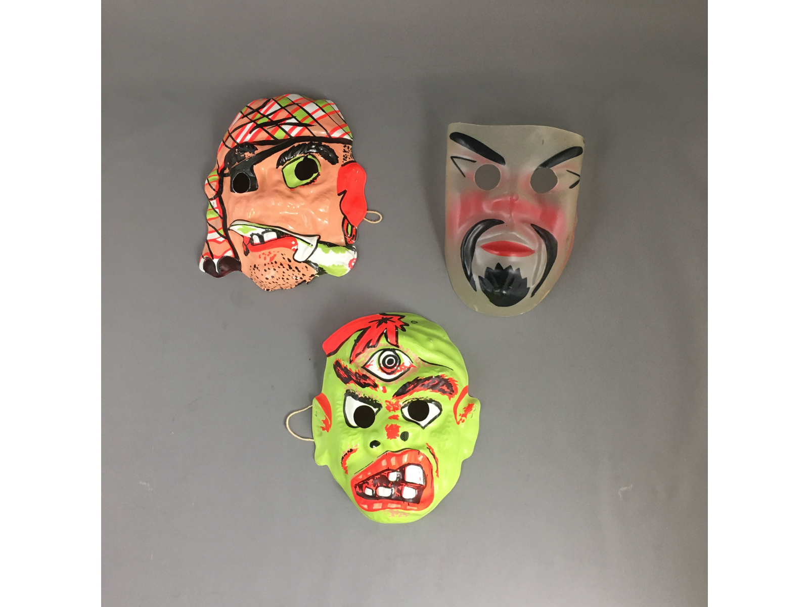 Three vintage Halloween masks for children of characters like a pirate, or a monster.