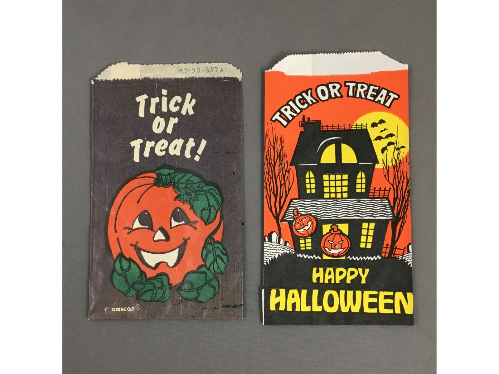 Two small vintage Halloween goodie bags. The bag on the left shows a grinning jack-o-lantern with the text "Trick of treat!", and the bag on the right shows a silhouetted house with leafless trees and bats flying overhead. Text on the right-side bag reads, "Trick or Treat / Happy Halloween".