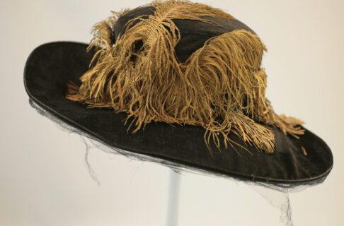 A wide-brimmed vintage women's hat; black, decorated with gold feathers.