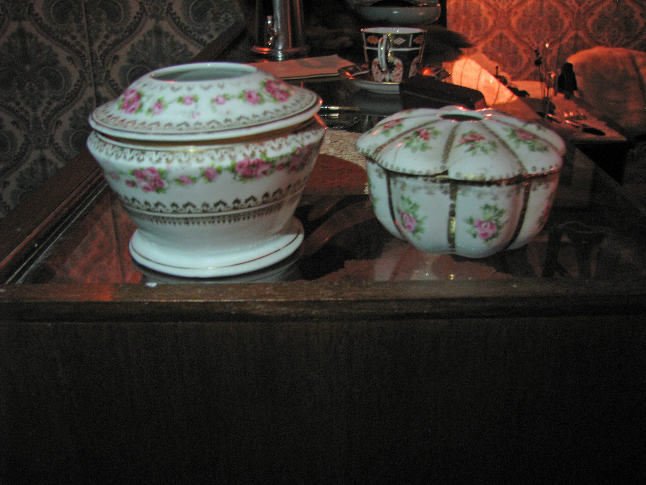 Two decorative bowls with pink rose patterns and small holes in the top of the lids.