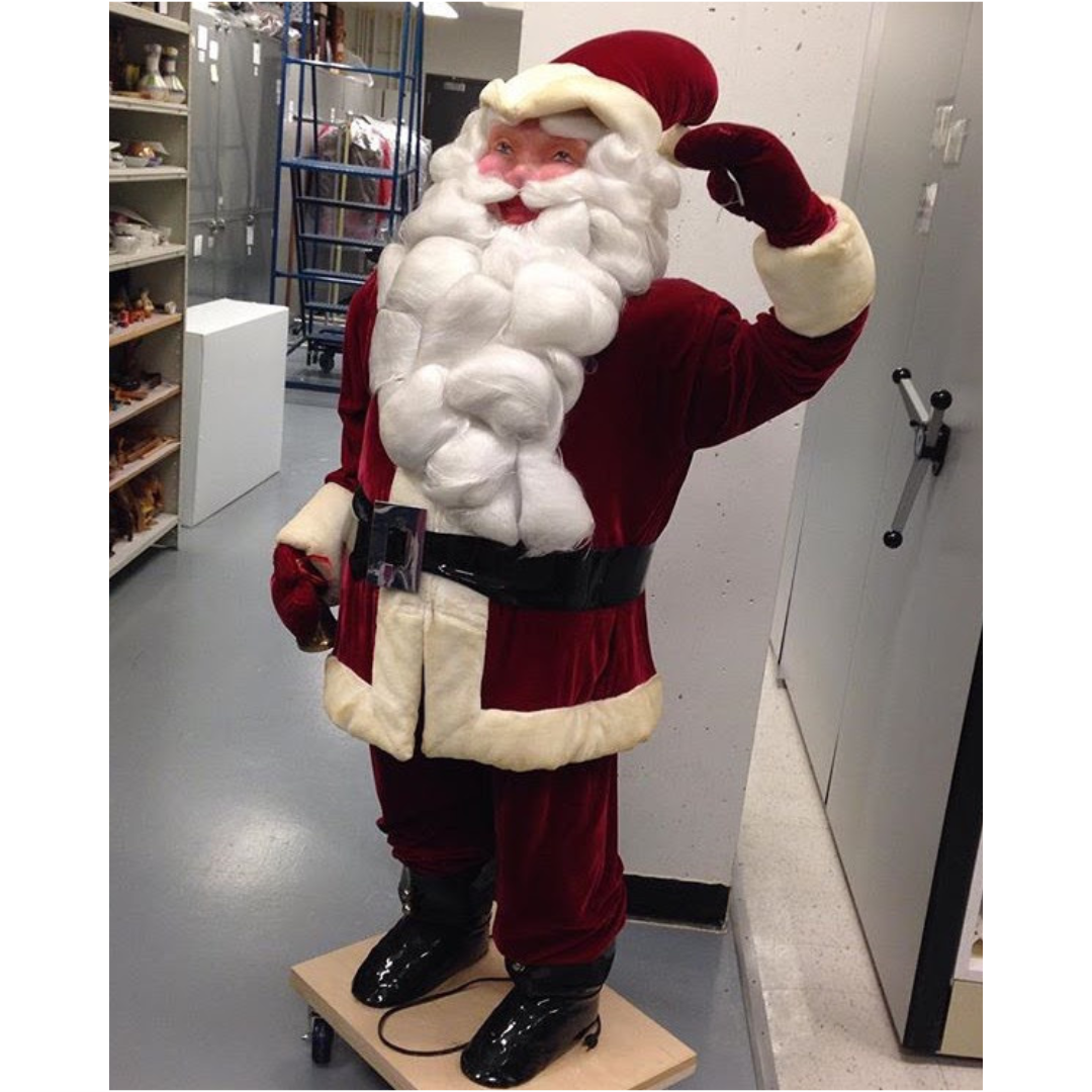 A large Santa Claus figurine with a hand raised in a wave.