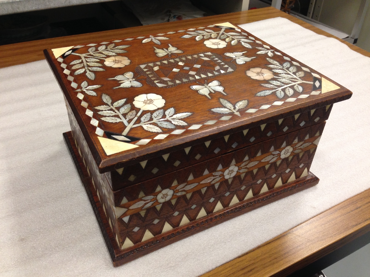 A wooden box inlaid with mother of pearl detailing in an intricate pattern.