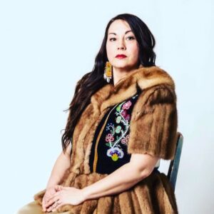 Seated formal headshot of Amy McPherson wearing a fur coat with a beaded front.