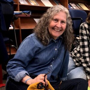 Informal photo of a smiling woman seated on the floor.