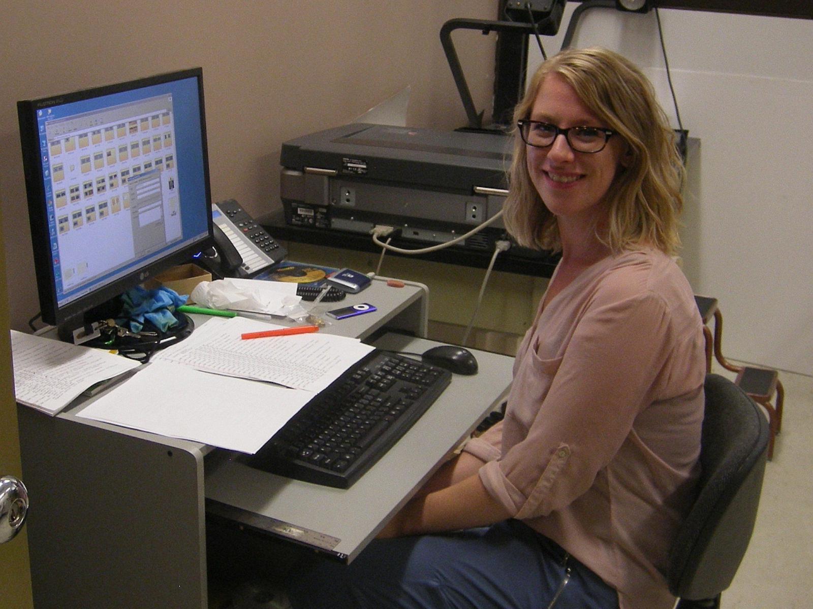 Summer student Jenna smiles towards the camera from her seat at a desk and computer.