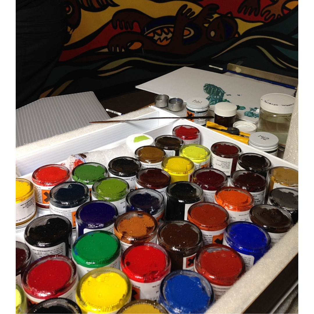 A tray of paint pots in a range of bright colours, with greens, reds, blues, browns, yellows, and more.