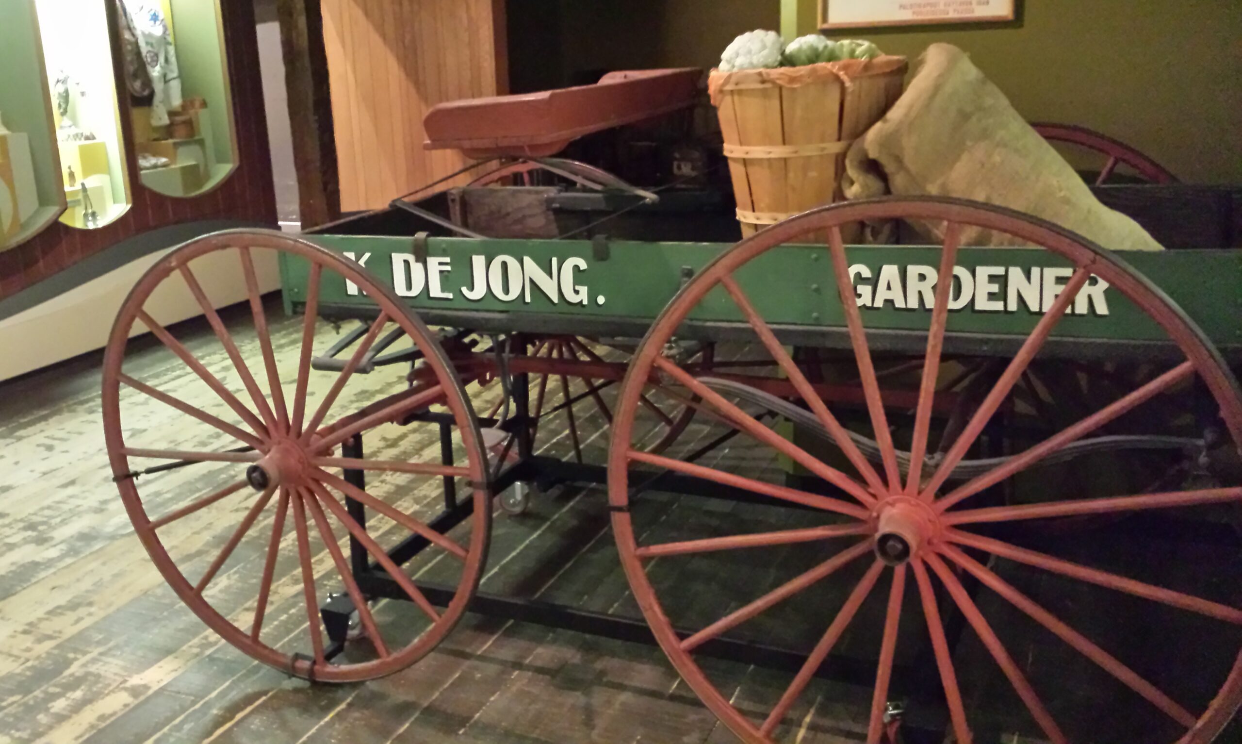 A shallow wagon with a green wagon box and red spoked wheels.