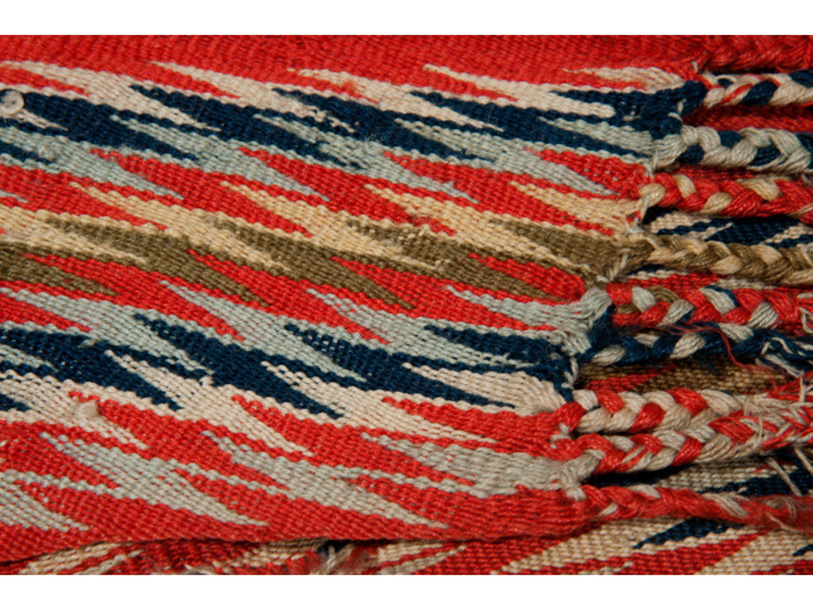 Close-up on the deatils of a woven fabric in red, blue, green, cream, and white.