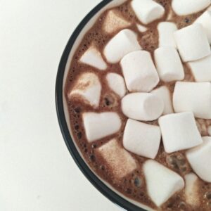 A close up on mini marshmallows floating in a mug of hot chocolate.