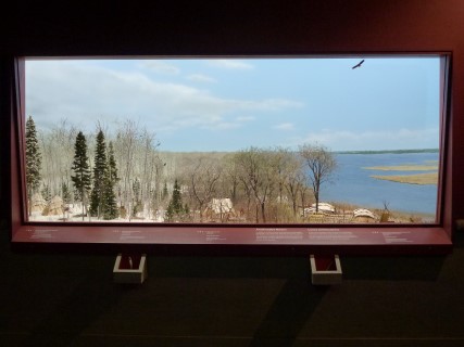 View into a mini diorama showing an area of land progressing through the seasons, and the adaptions of the people living there during each season.