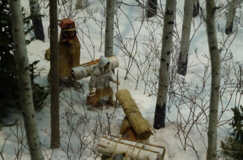 A child figure in a miniature diorama winter scene, wearing traditional winter gear of woven rabbit fur.