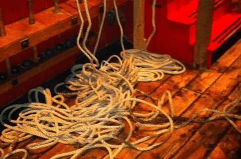 A pile of loose rope on the wooden deck of a ship.