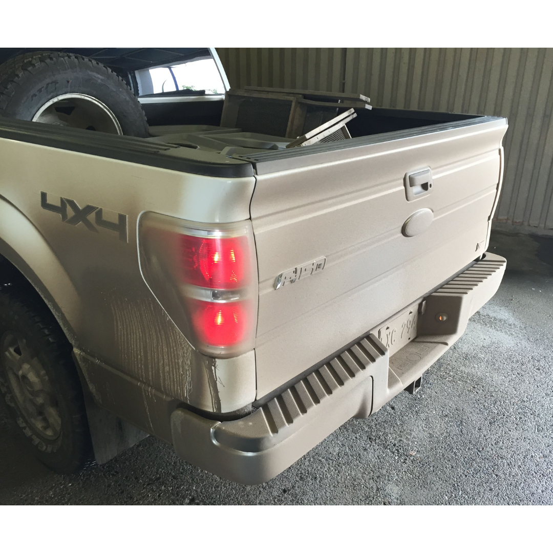 The rear end of a very dusty, dirty truck.