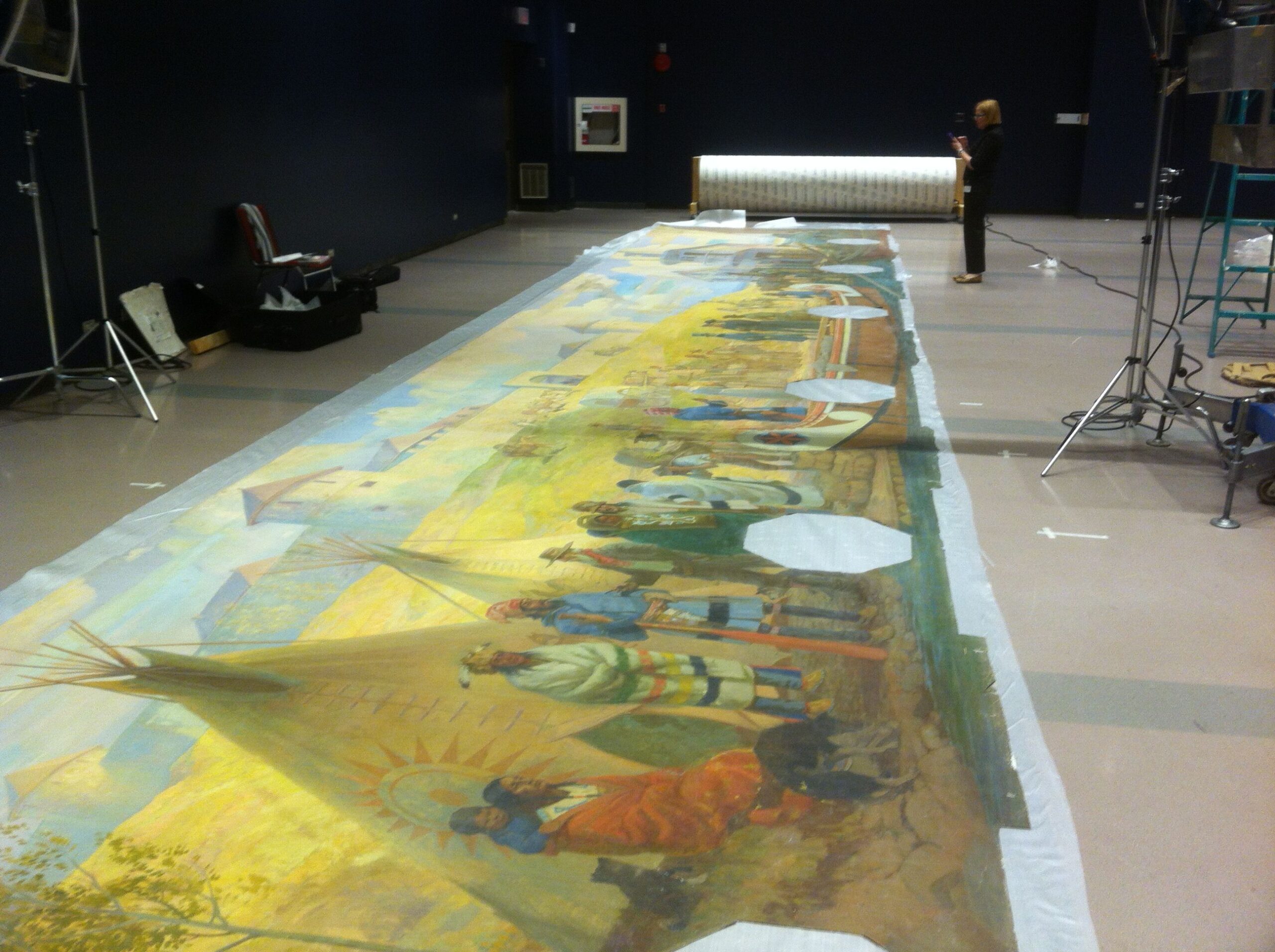 An oversized mural rolled out on the floor of a large space.