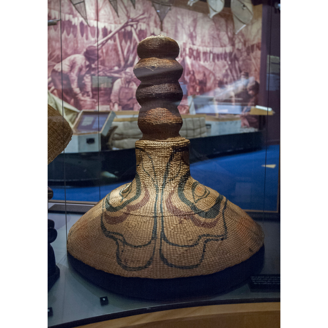 A conical shaped woven hat with four ball like forms stacked on the top.