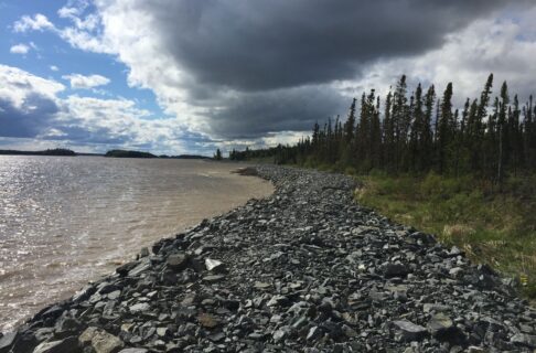 View down a rocky shoreline with dark clouds gathering overhead.