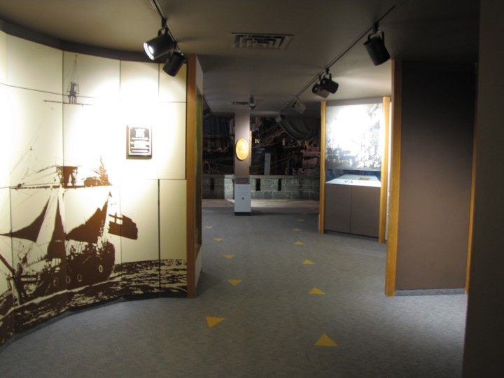 Looking down a weaving hallway with two rows of arrows directing visitors both down and up the hallway.