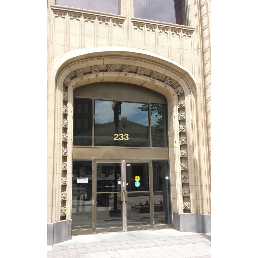 A neo-Gothic building entrance in light cream stone with a tall arched doorway.