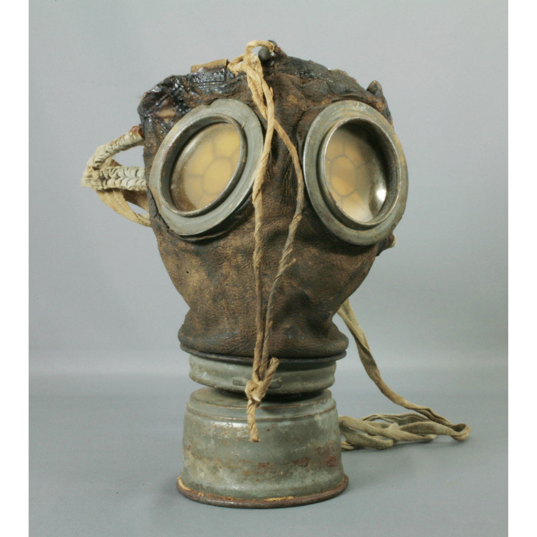 A gas mask with large screened eye windows and a tubular breathing vent.