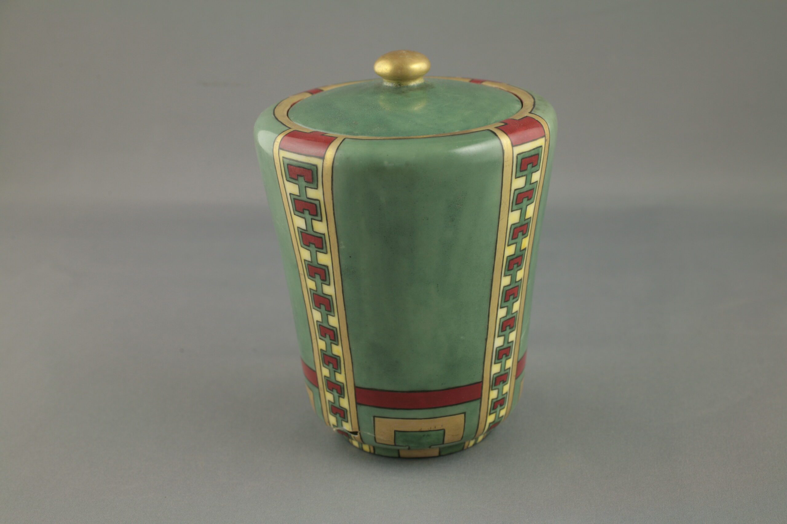 A French Limoges jar painted in a mid-tone green with red and gold detailing.