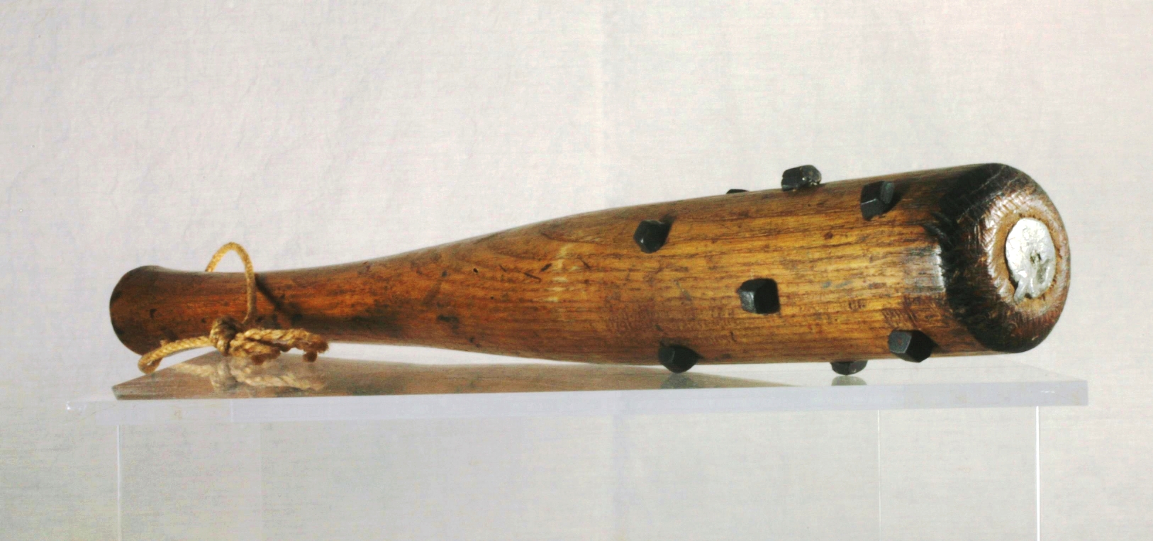 A wooden club with a metal core visable from the top, and hobnails affixed to the sides.