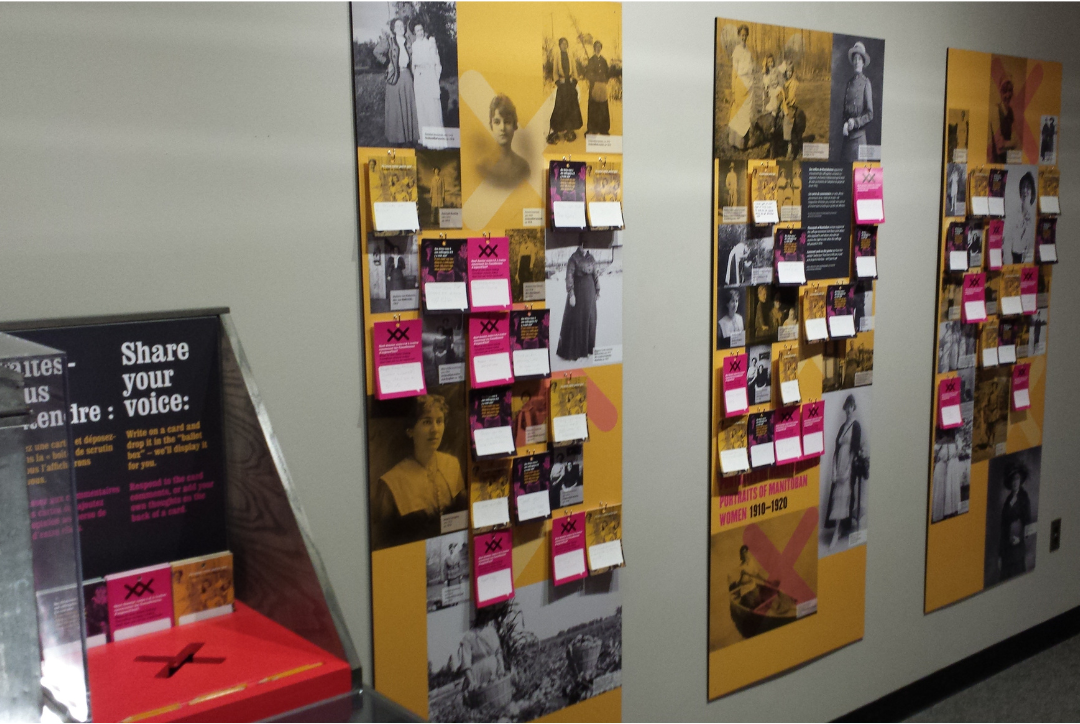 The “Nice Women Don’t Want the Vote” exhibit, with a branded ballot box and three panels along the wall, each with response cards stuck to it by visitors.