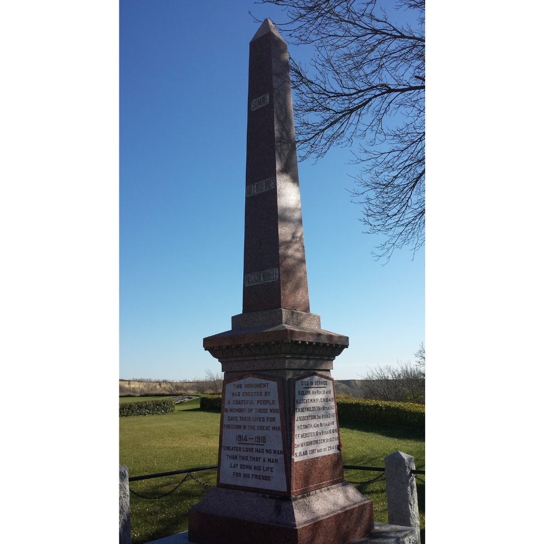 A pillar like war memorial in a green field.