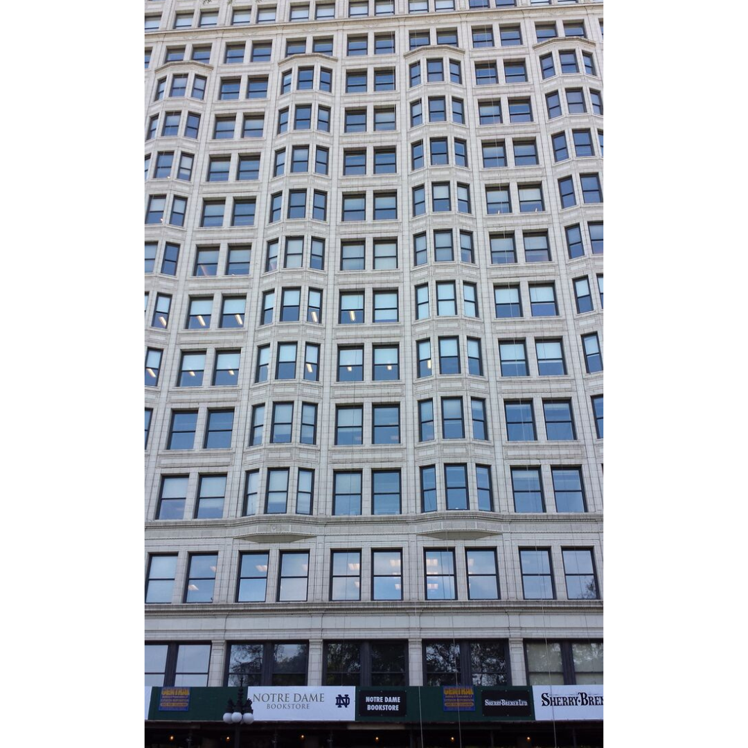 Looking up the side of a skyscraper full or windows, with alternating flat and bay windows.