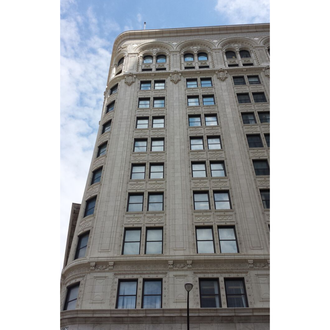 A tall building of white stone, with a rounded end on the left.