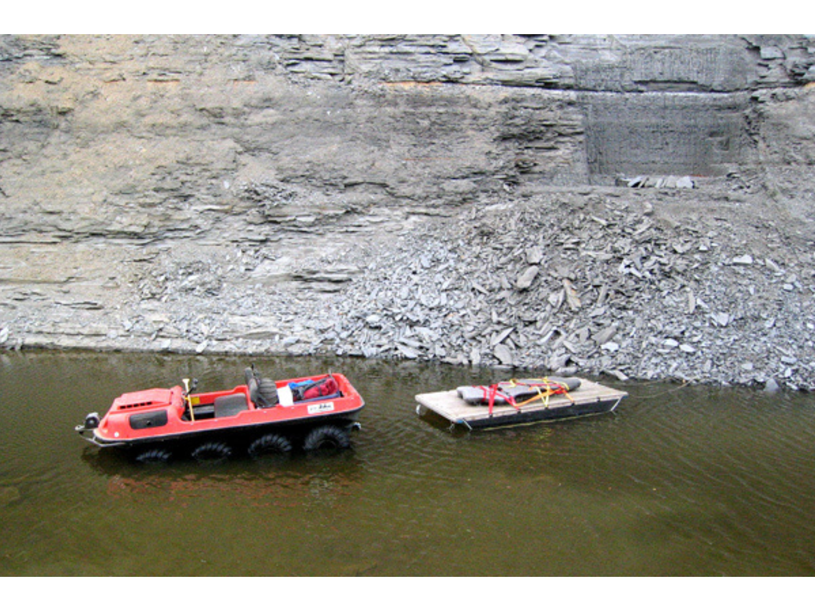 A large fossil slab strapped to a raft attached to the back of an Argo water vehicle.