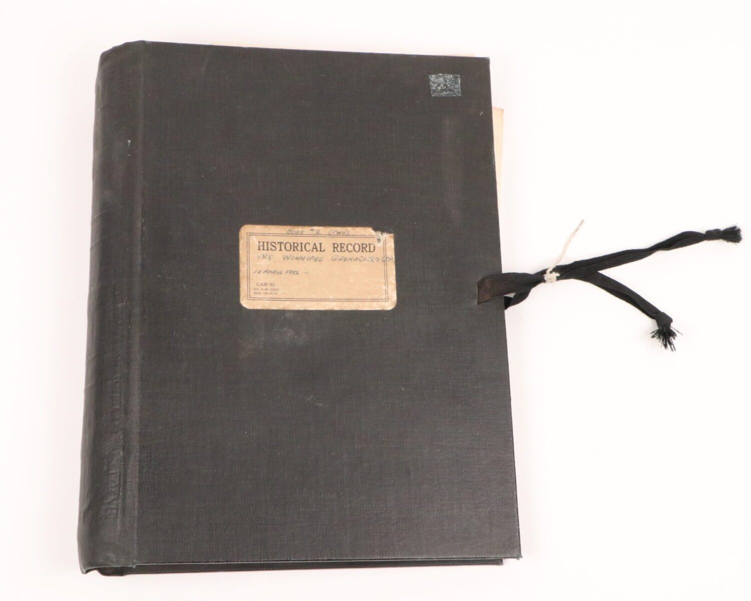 Black book with a white rectangular label on the front cover and a silk ribbon tie closing it together.