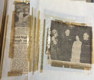 Loose pages of a scrapbook with newspaper clippings attached to paper with yellowed tape.