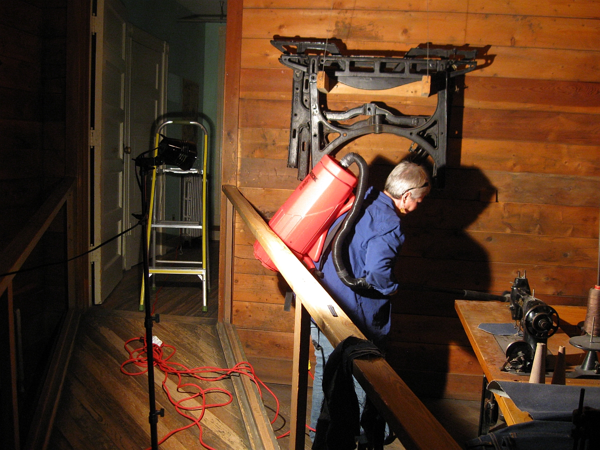 An individual wearing a red backpack vacuum cleaning artifacts and the space in the Winnipeg 1920 Cityscape.