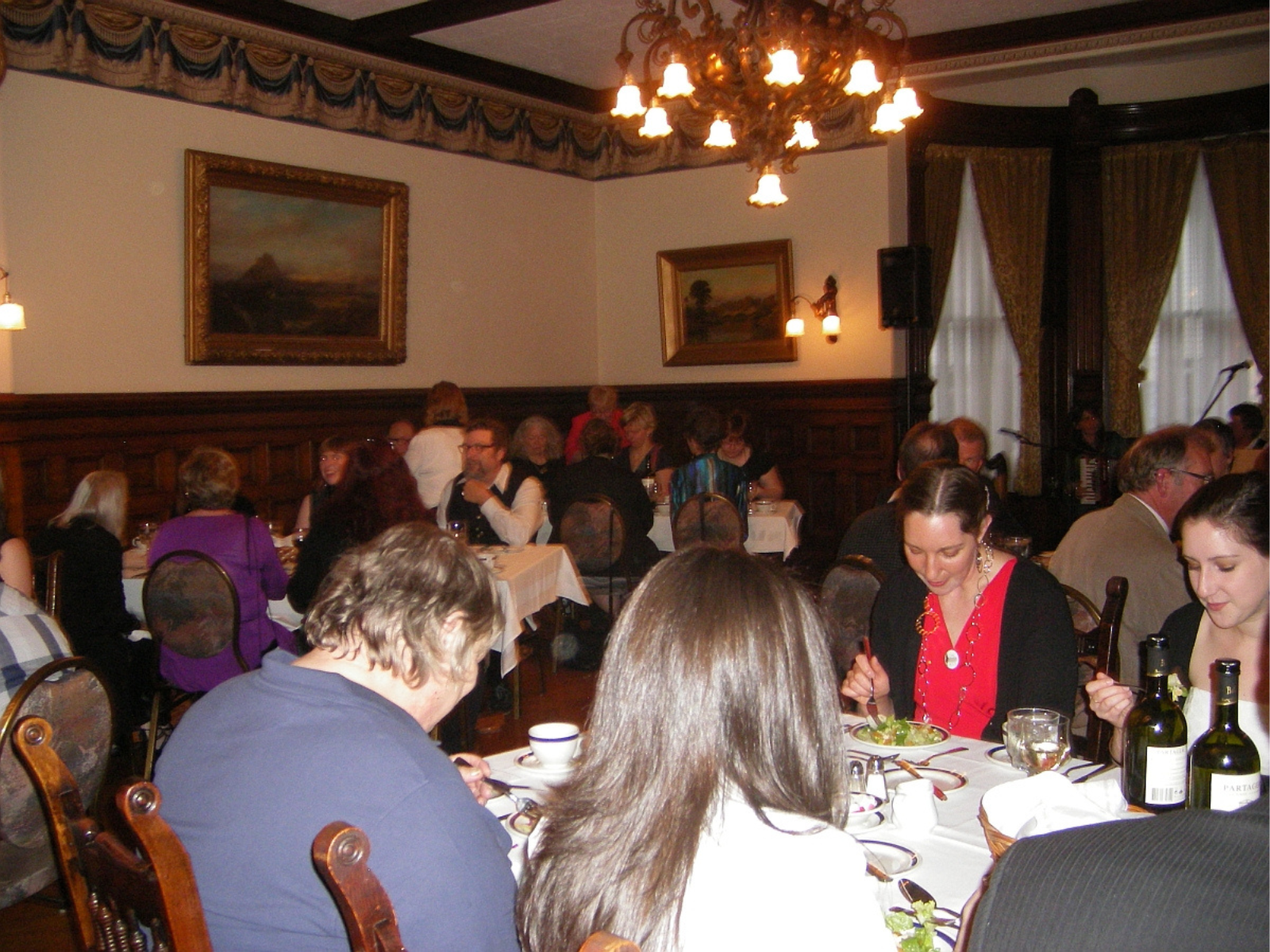 Interior room in a historic house with people seated around tables laid around the room.