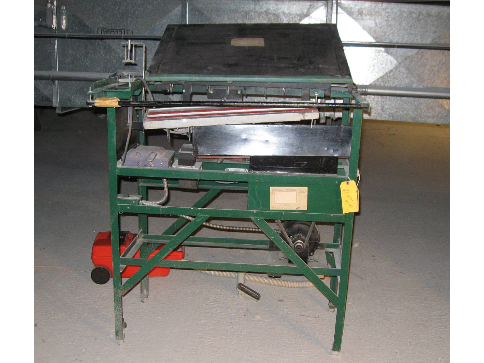 A large metal egg grader next to an orange vacuum cleaner.