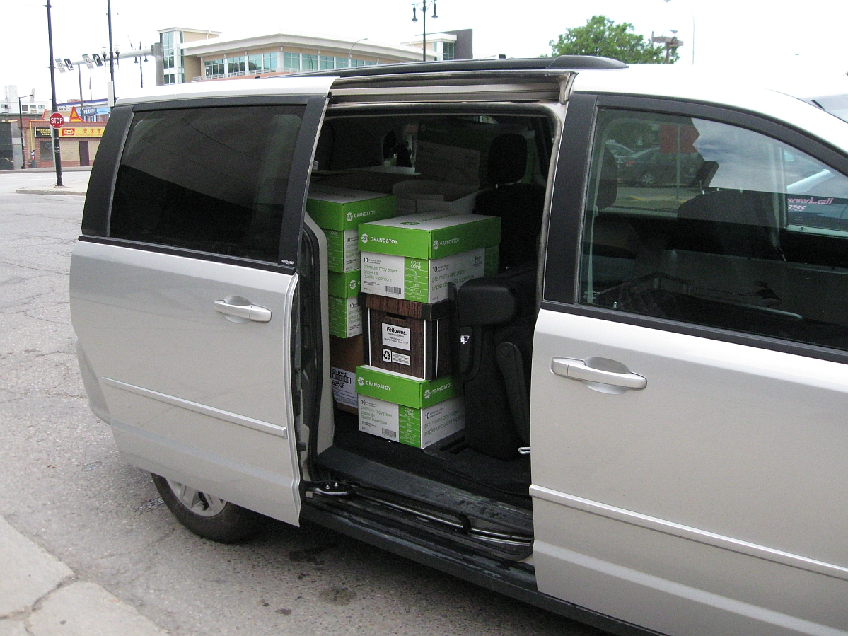 Photo of a mini van with the side door open, and file storage boxes stacked in the back of the van.