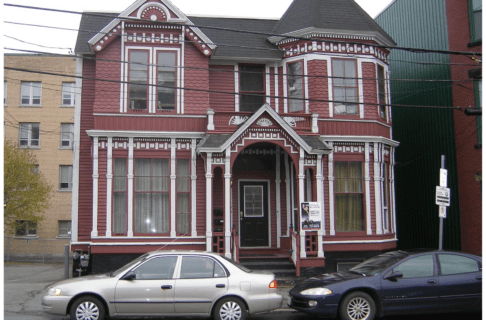 The exterior of a large red historic house with white trim.