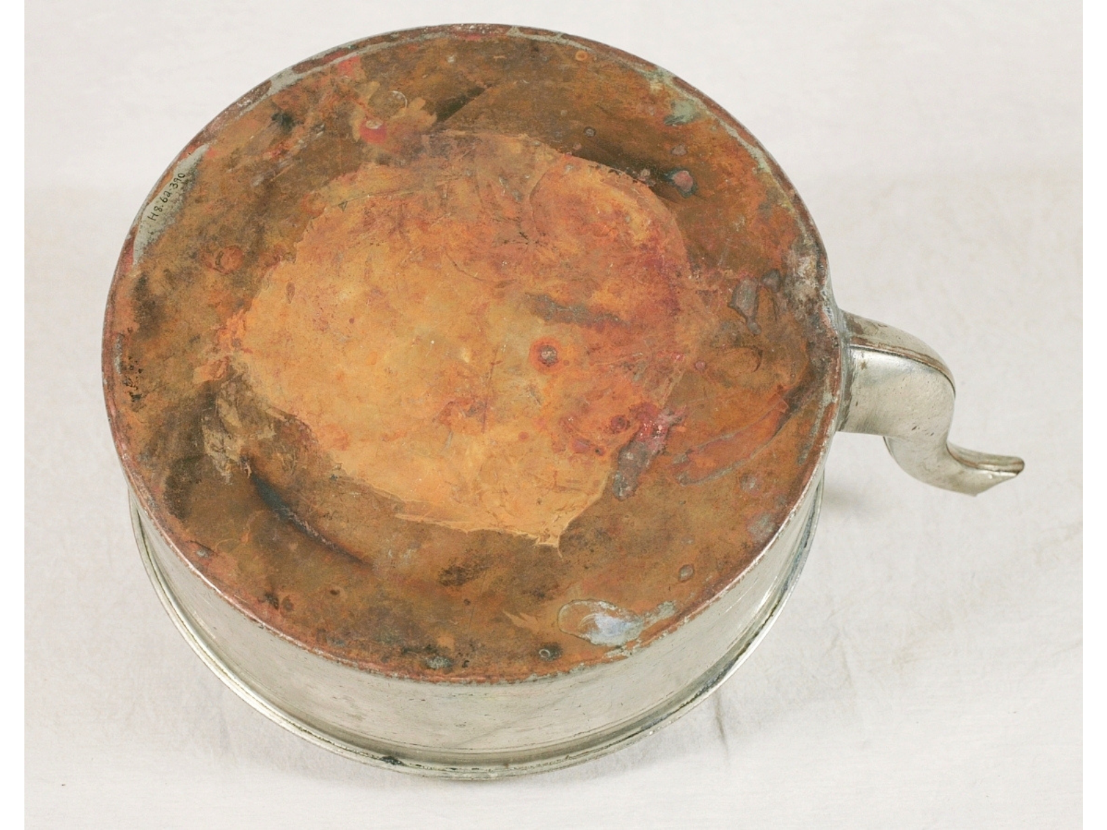 The bottom of a large silver kettle with a stain on the bottom, but the remnants of the adhesives removed.