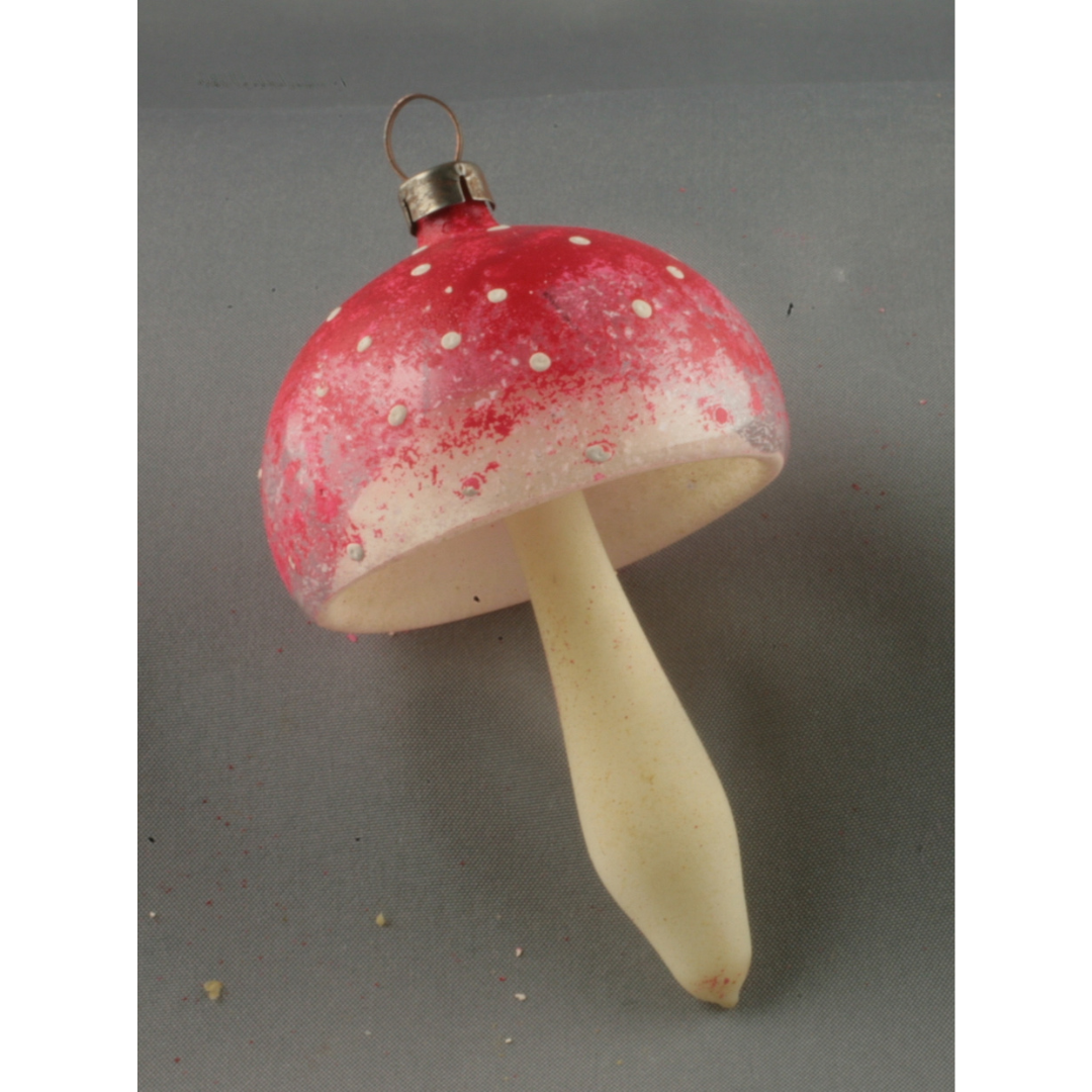 A delicate glass ornament shaped like a mushroom with a hollow red cap and white stem.