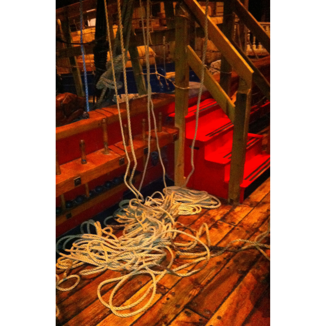 A pile of loose rope on the wooden deck of a ship.