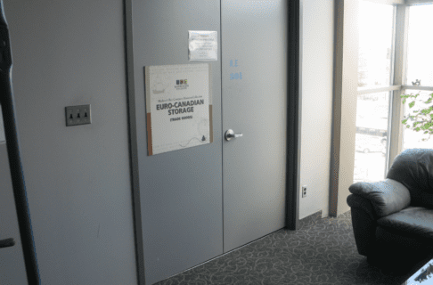 Photo looking at the closed double doors of a museum storage room. A large sign on one of the doors reads, "Hudson's Bay Company Museum Collection / Euro-Canadian Storage / (Trade Goods)".