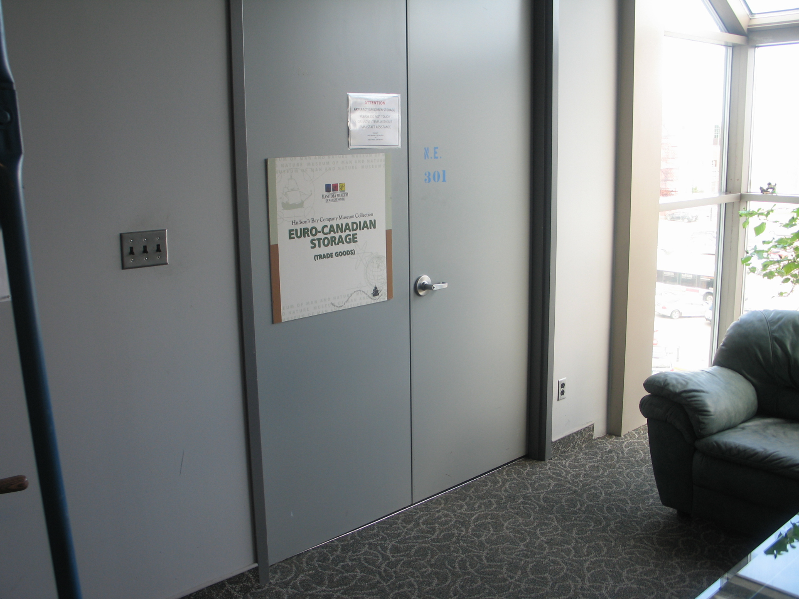 Photo looking at the closed double doors of a museum storage room. A large sign on one of the doors reads, "Hudson's Bay Company Museum Collection / Euro-Canadian Storage / (Trade Goods)".