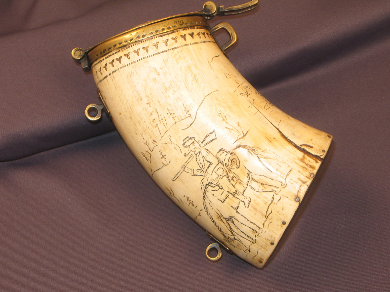 Close-up on the other side of a horn cannister with an engraving depicting an individual on a horse.