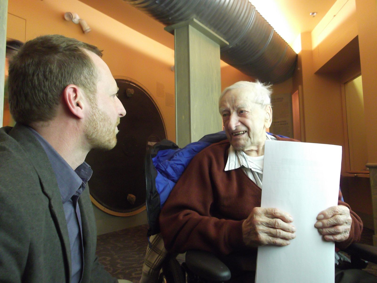 Two individuals sitting next to each other in conversation in the Parklands Gallery of the Manitoba Museum.