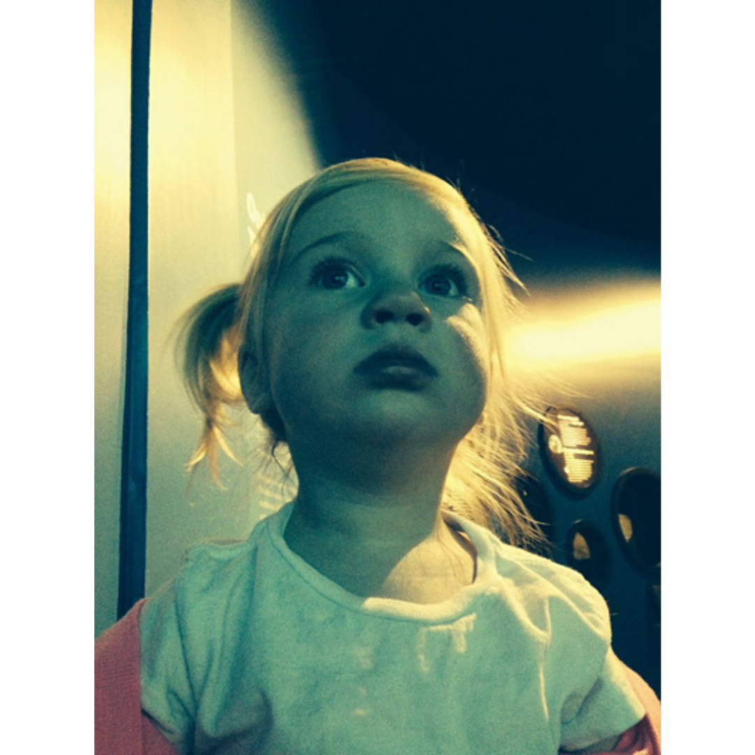 Photograph looking up into the face of a young child looking up at a museum display behind the camera.