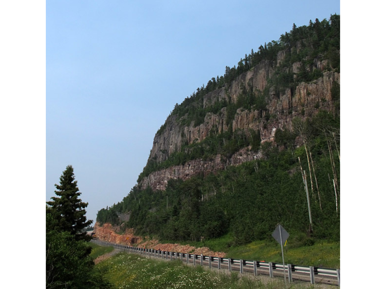 View of a large rocky hillside next to a roadway.