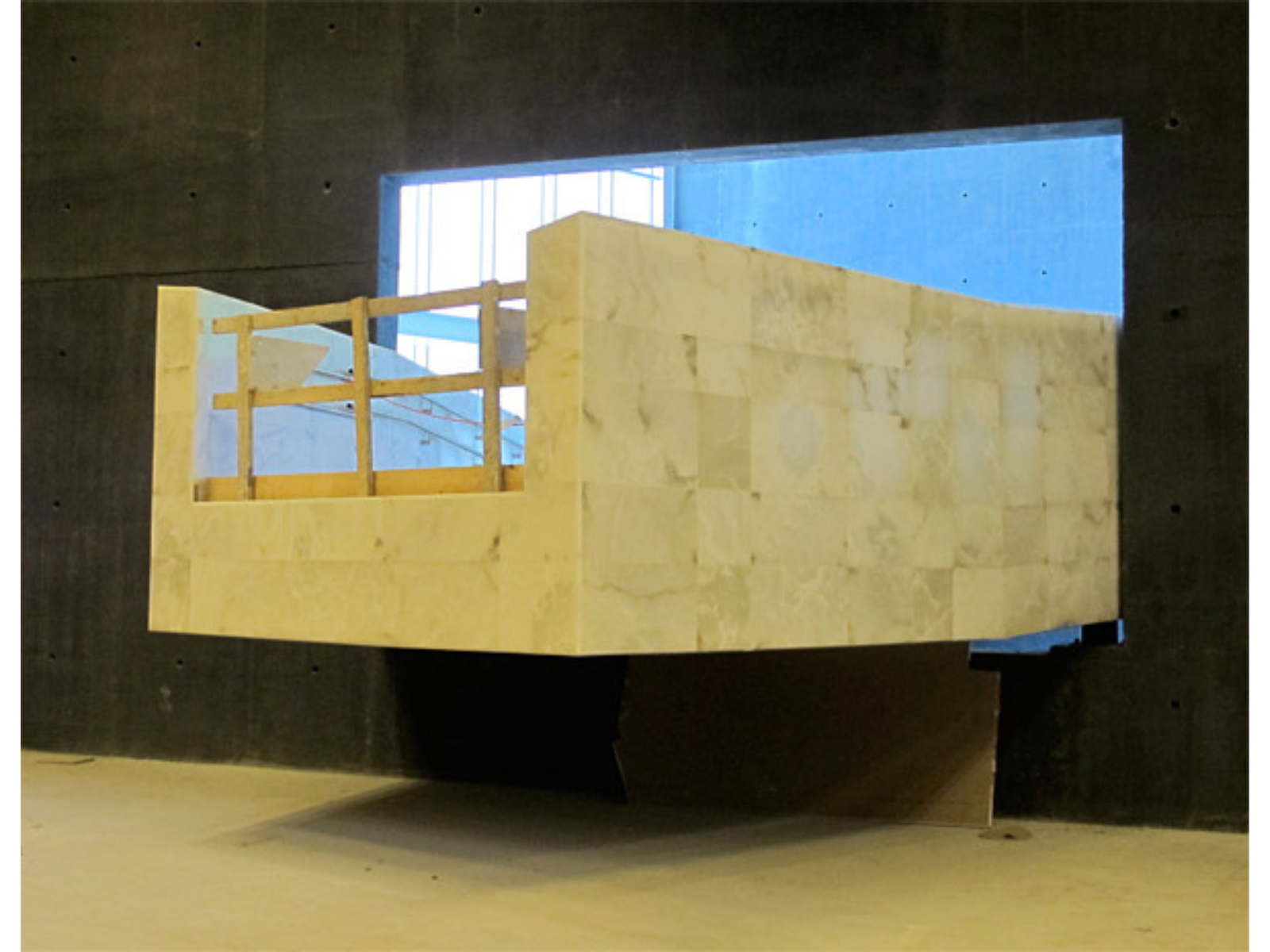 The incomplete end of a large alabaster ramp with a barricade at the end as it is still under construction.