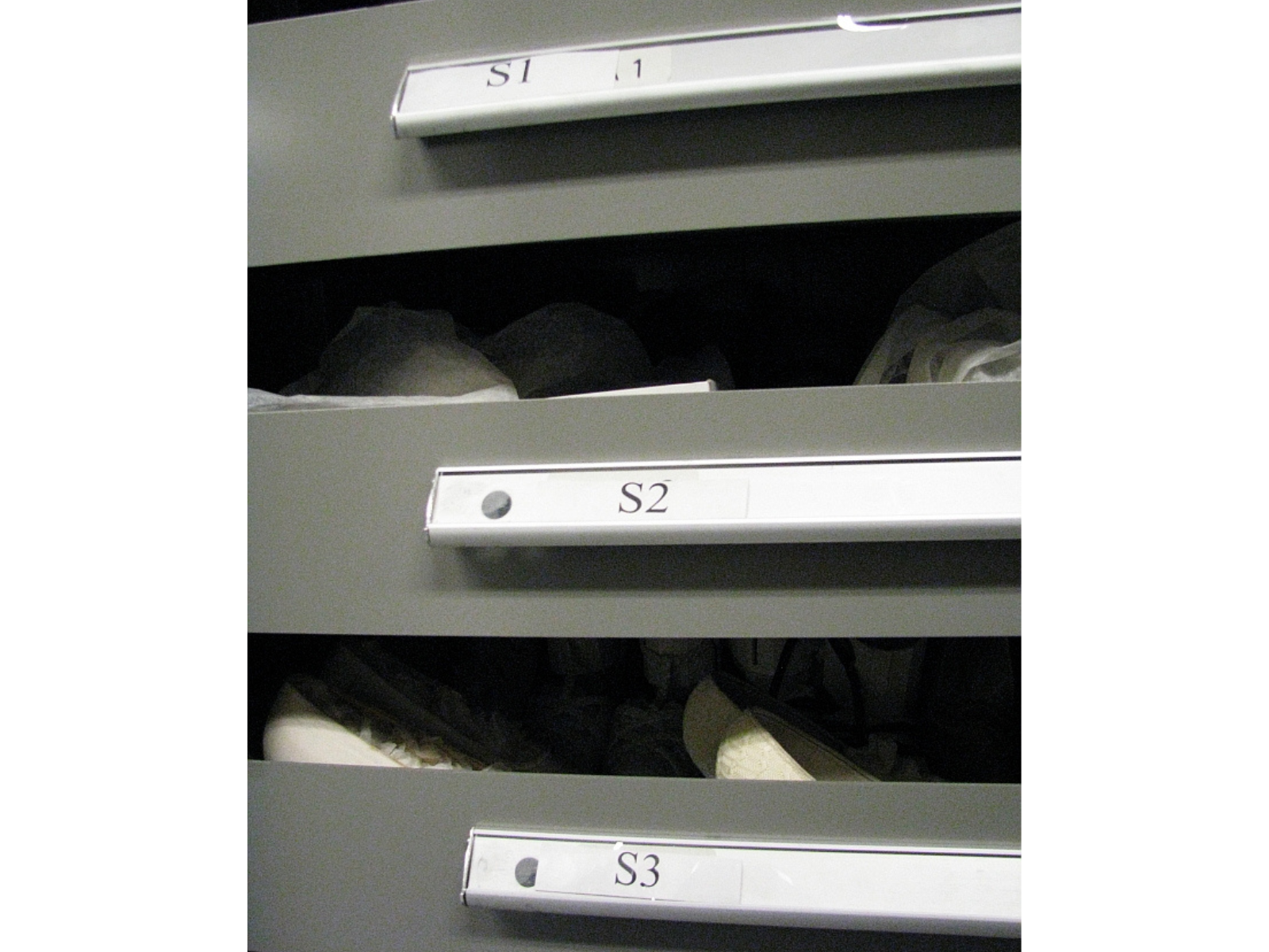 Close up on the labels of three shallow storage drawers, labelled S1, S2, and S3.