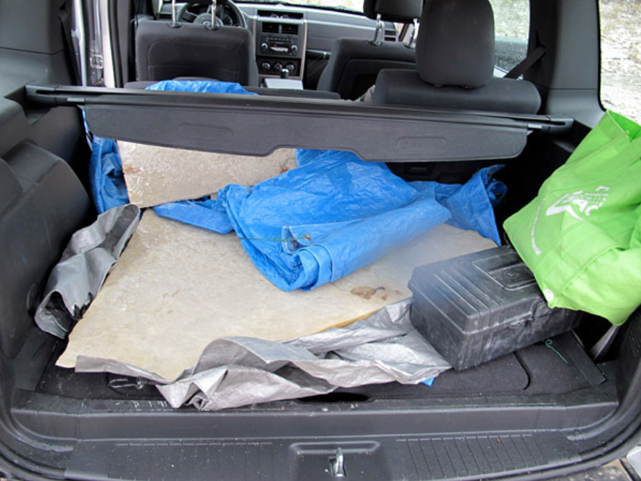 Two large slabs of rock lying on tarps in the back of a vehicle.