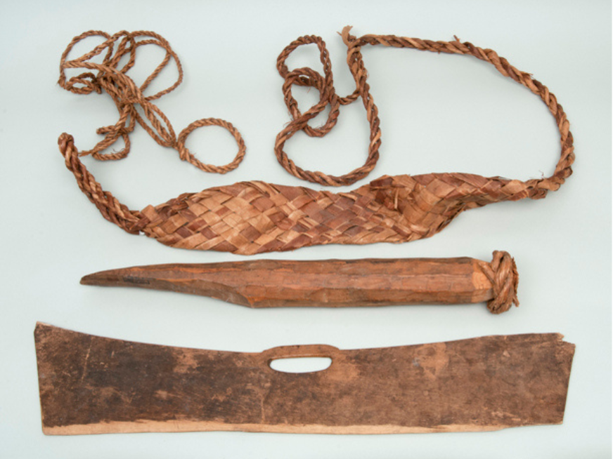 A collection of copper coloured artifacts - a harness, yew wedge, and bark pounder.